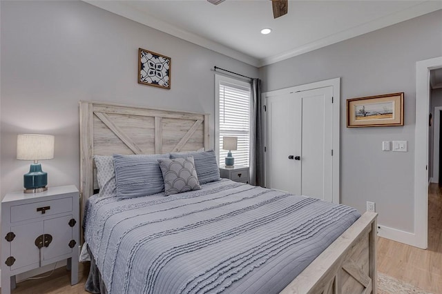 bedroom with a ceiling fan, baseboards, light wood-style floors, ornamental molding, and a closet