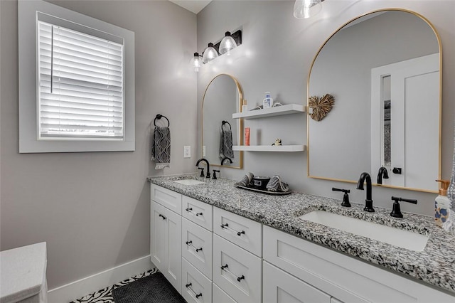 full bath featuring a sink, baseboards, and double vanity