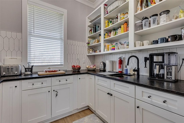 kitchen featuring open shelves, dark countertops, a sink, and white cabinets