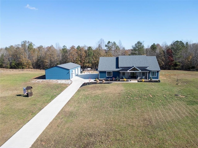 view of front of house with a garage, an outbuilding, a forest view, and a front lawn