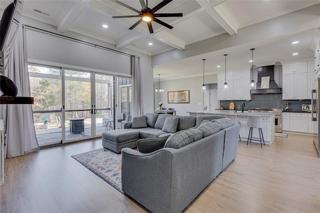 living area with light wood finished floors, ceiling fan, coffered ceiling, and beamed ceiling