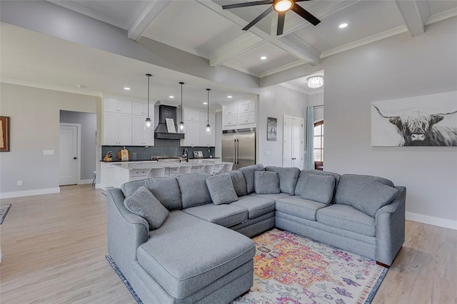 living room featuring ornamental molding, beam ceiling, light wood-style flooring, and baseboards