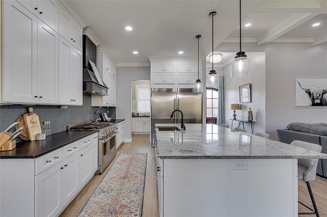 kitchen with a breakfast bar area, high end appliances, backsplash, light wood-style flooring, and wall chimney range hood