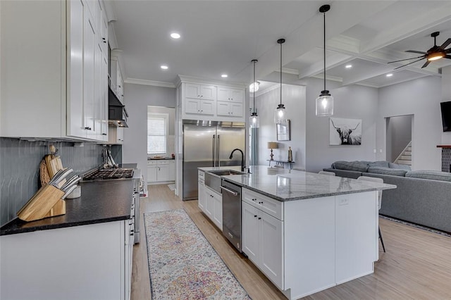 kitchen featuring high end stove, white cabinetry, open floor plan, and a sink