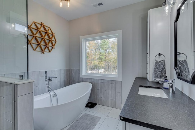 full bath with visible vents, a soaking tub, marble finish floor, vanity, and tile walls