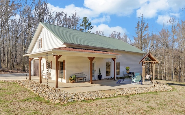 exterior space featuring a garage, metal roof, a patio area, and driveway