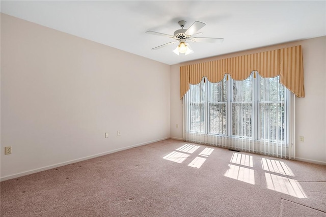 carpeted spare room featuring ceiling fan and baseboards