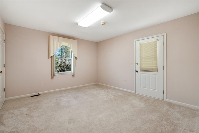 empty room featuring baseboards, visible vents, and light colored carpet