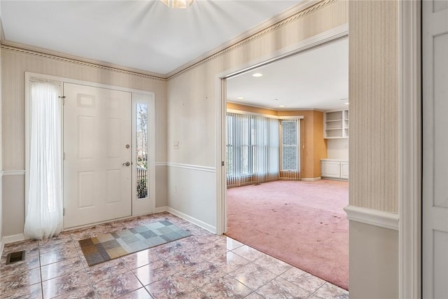 entryway with baseboards, ornamental molding, visible vents, and light colored carpet