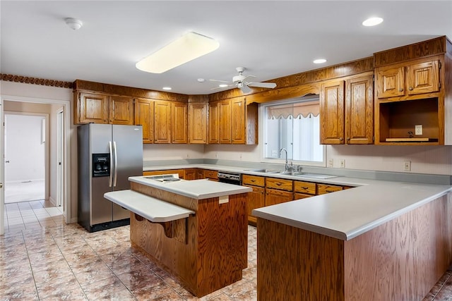 kitchen with a kitchen island, a ceiling fan, light countertops, brown cabinetry, and stainless steel fridge