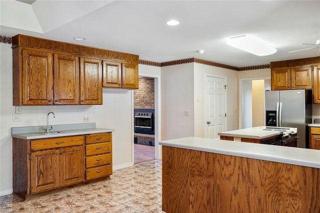 kitchen with recessed lighting, a sink, light countertops, appliances with stainless steel finishes, and brown cabinets