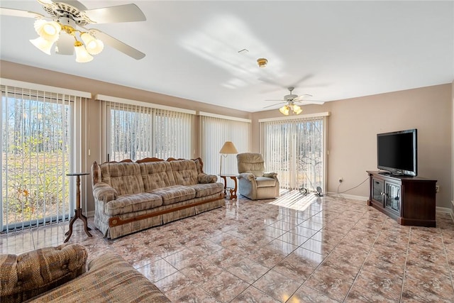 living area with light tile patterned floors, ceiling fan, and baseboards