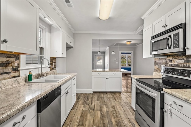 kitchen with crown molding, stainless steel appliances, a sink, white cabinets, and pendant lighting