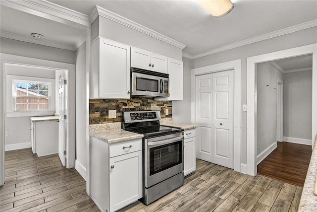 kitchen with light wood finished floors, tasteful backsplash, appliances with stainless steel finishes, and white cabinets