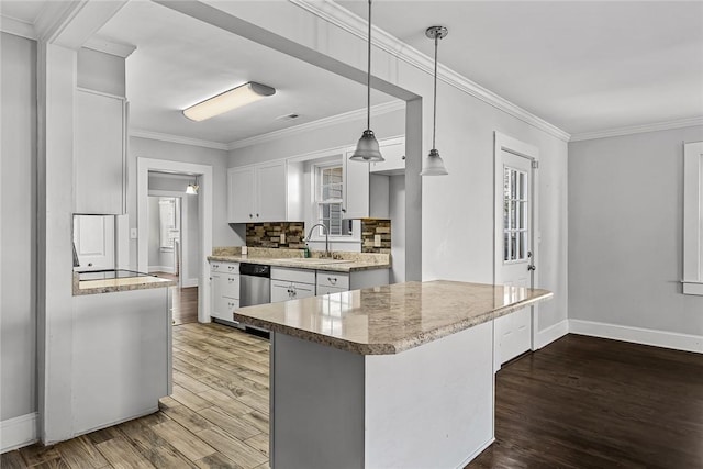 kitchen with decorative light fixtures, a sink, a peninsula, and white cabinetry