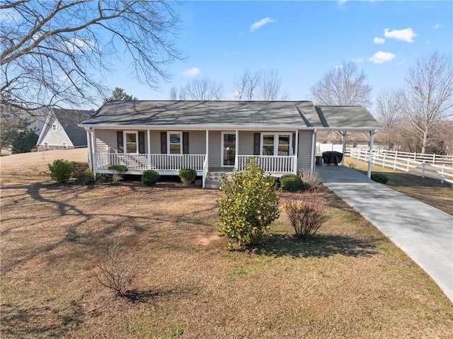 ranch-style house with covered porch, fence, concrete driveway, a carport, and a front lawn