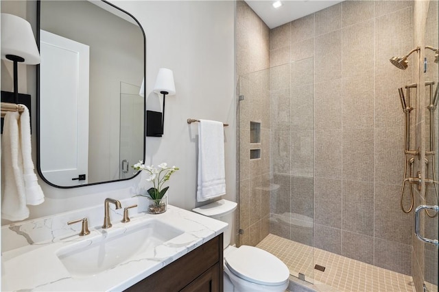 full bath featuring toilet, vanity, and a shower stall