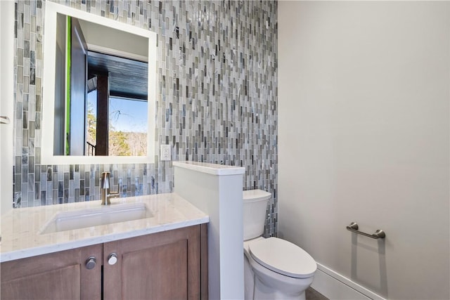 half bathroom with tile walls, vanity, toilet, and decorative backsplash