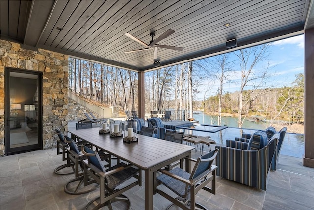 view of patio / terrace featuring ceiling fan, outdoor dining area, a water view, and stairs