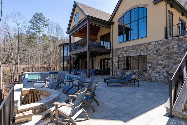 view of patio with a balcony and an outdoor fire pit