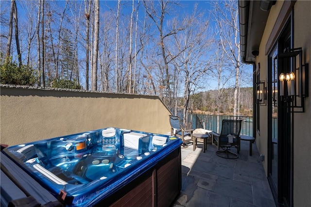 view of patio with a hot tub and fence