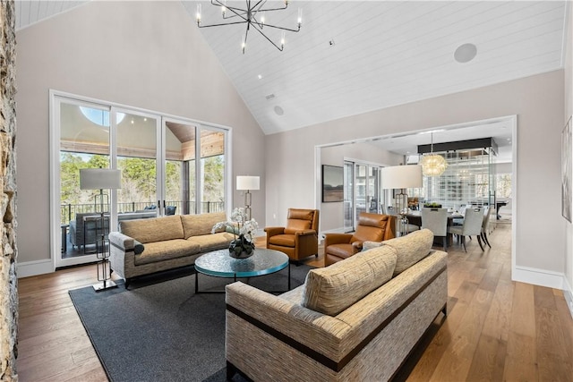 living area with light wood-style floors, high vaulted ceiling, baseboards, and an inviting chandelier