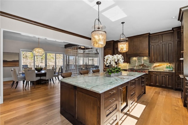 kitchen with hanging light fixtures, light stone counters, a kitchen island, and dark brown cabinetry