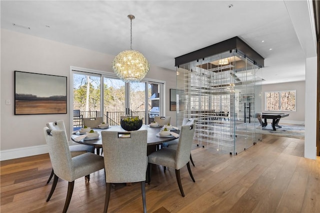 dining room featuring a wealth of natural light, baseboards, an inviting chandelier, and wood finished floors