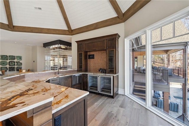 kitchen featuring vaulted ceiling with beams, light countertops, visible vents, dark brown cabinets, and a peninsula