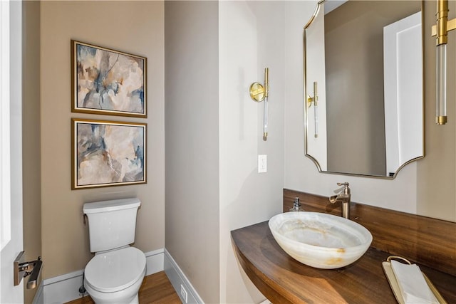 half bath with vanity, toilet, and baseboards