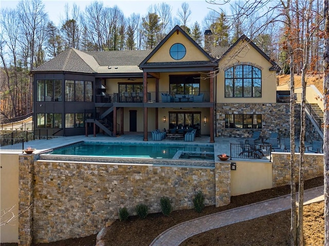 back of property with a chimney, stucco siding, a patio area, an outdoor pool, and stairs