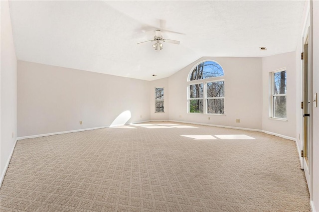 empty room featuring visible vents, baseboards, a ceiling fan, light colored carpet, and lofted ceiling