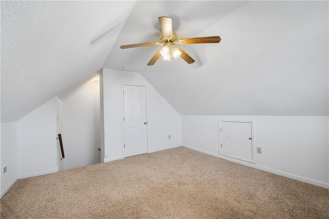 additional living space with carpet floors, ceiling fan, vaulted ceiling, and a textured ceiling