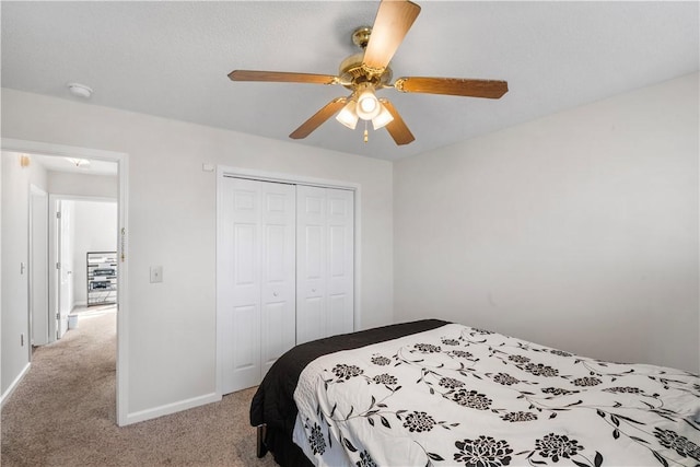 bedroom featuring light carpet, ceiling fan, baseboards, and a closet