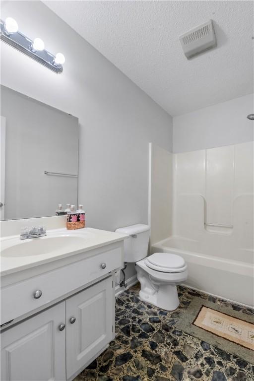 bathroom with a textured ceiling, toilet, visible vents, vanity, and shower / bathing tub combination