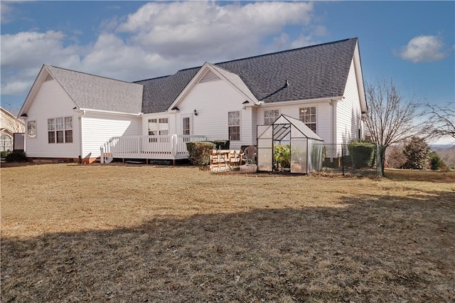 rear view of property with a wooden deck, a shingled roof, a yard, an outdoor structure, and an exterior structure