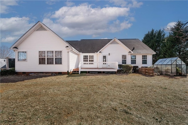 back of property featuring a greenhouse, an outbuilding, crawl space, a deck, and a yard