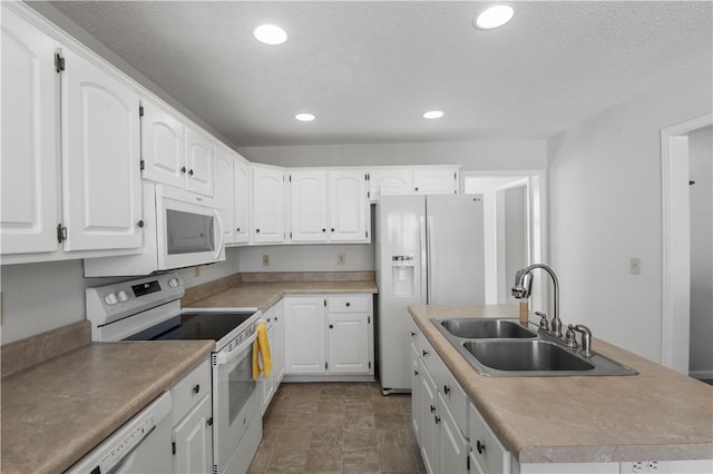 kitchen featuring white appliances, a center island with sink, white cabinets, a sink, and recessed lighting