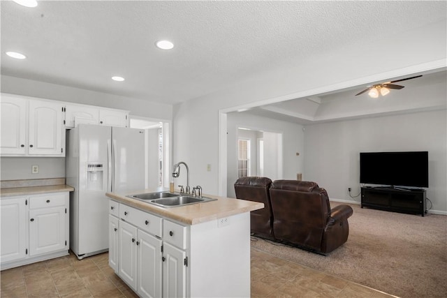 kitchen with an island with sink, open floor plan, light countertops, white cabinetry, and a sink