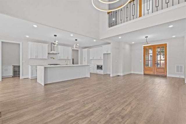 unfurnished living room featuring french doors, light wood-style flooring, visible vents, and baseboards