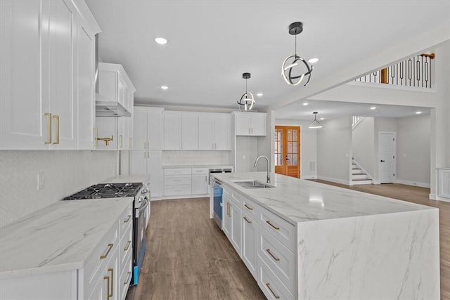 kitchen with a sink, white cabinets, a large island, appliances with stainless steel finishes, and decorative light fixtures