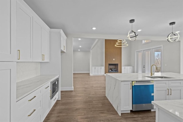 kitchen featuring white cabinets, appliances with stainless steel finishes, light stone countertops, pendant lighting, and a sink