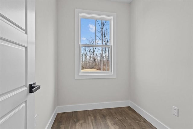 spare room with dark wood-style flooring and baseboards