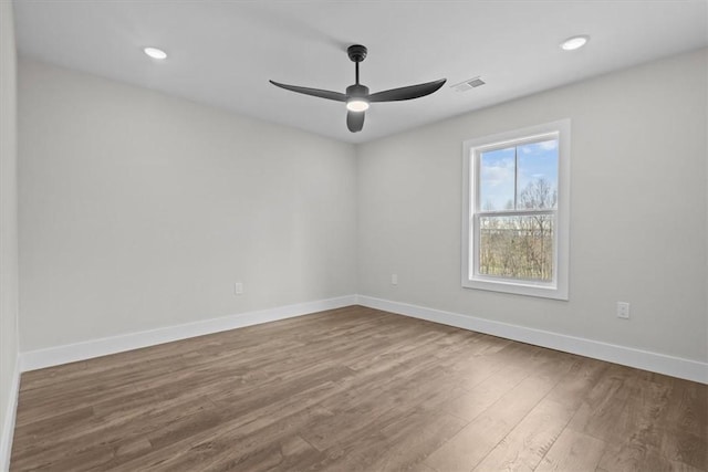 empty room with a ceiling fan, visible vents, baseboards, and wood finished floors