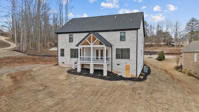 rear view of house featuring roof with shingles, a porch, and crawl space