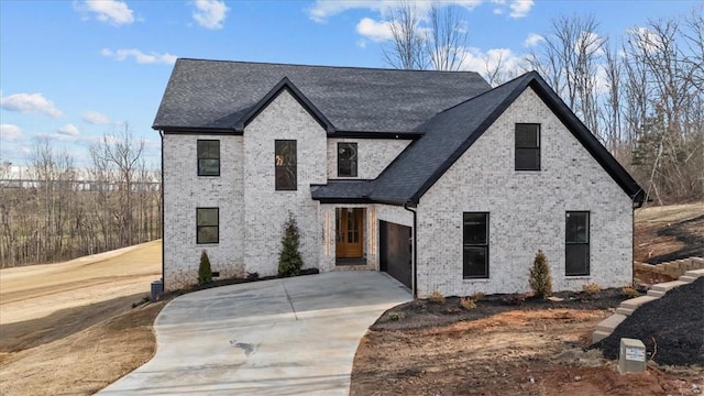 view of front of property featuring a shingled roof, brick siding, and driveway