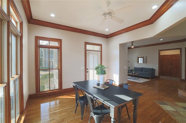 dining room featuring ceiling fan, crown molding, baseboards, and wood finished floors