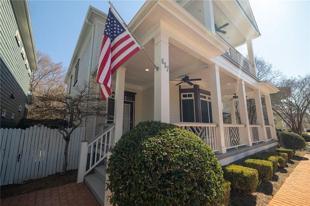 view of home's exterior with a balcony, covered porch, ceiling fan, and fence