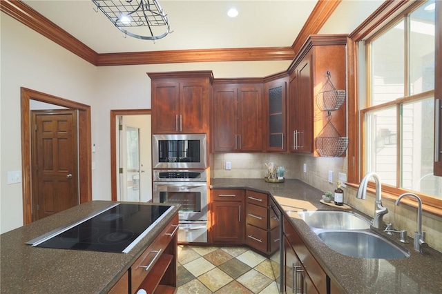 kitchen with glass insert cabinets, a sink, crown molding, black appliances, and backsplash