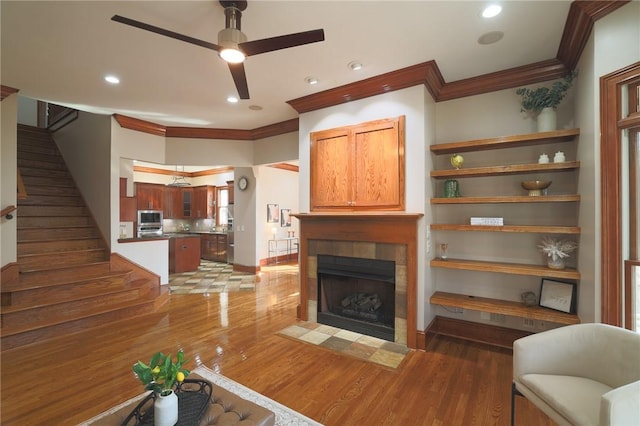 living room with recessed lighting, light wood-style flooring, ornamental molding, and a tile fireplace